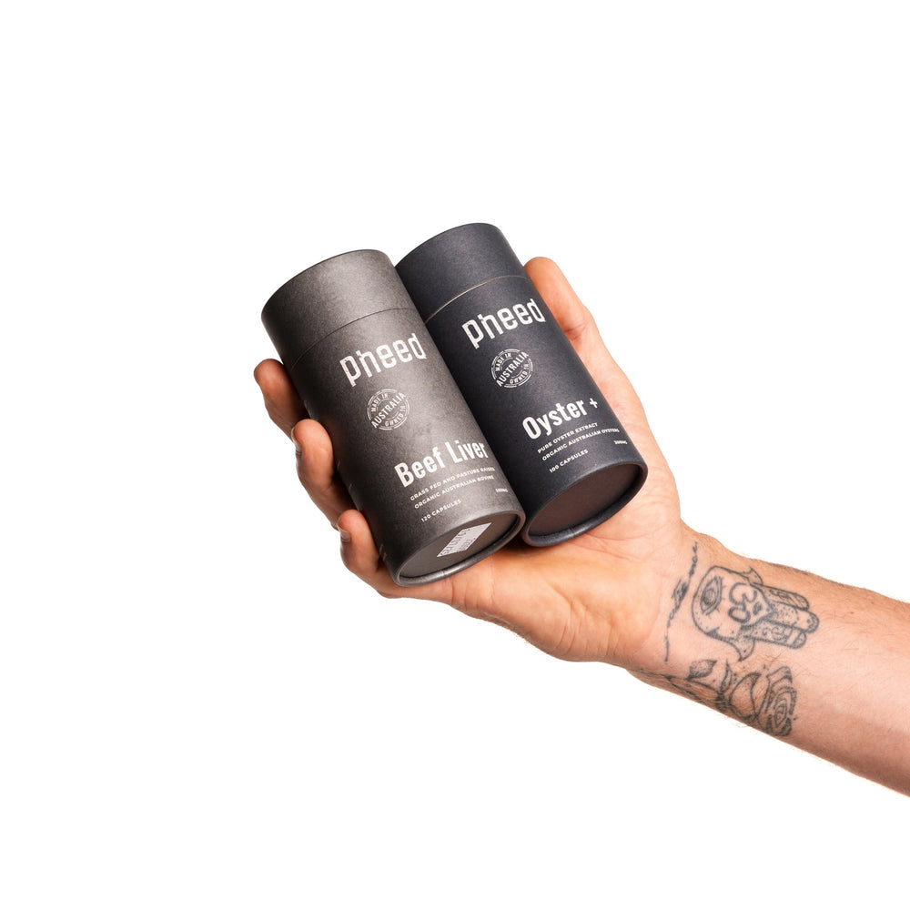 Hand holding Pheed Beef Liver and Oyster+ supplements from the Performance Pack.