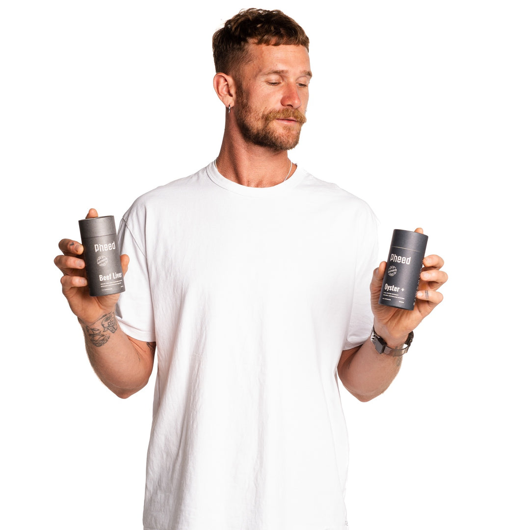 Man holding Pheed Beef Liver and Oyster+ capsules on a white background.
