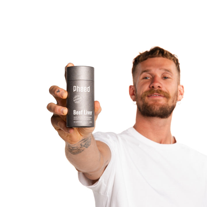 Man holding a 120-capsule bottle of Pheed Beef Liver Capsules against a white background.