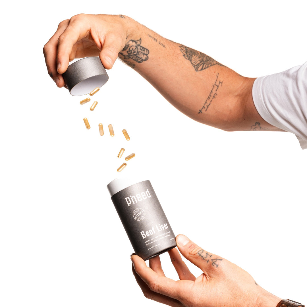 Pheed Beef Liver Capsules with capsules being poured into the 120-capsule bottle.