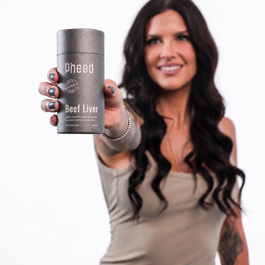 Woman holding Pheed Beef Liver Capsules 120-capsule bottle towards the camera.