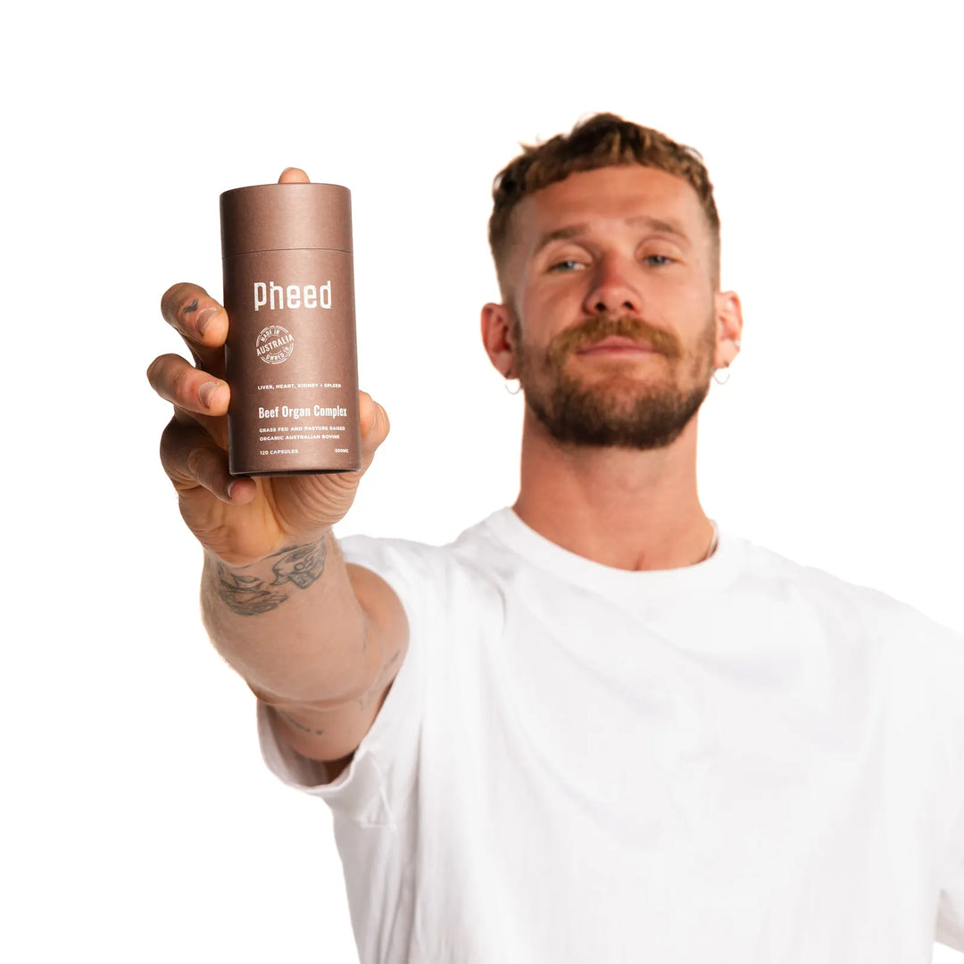 Man in a white T-shirt holding a Pheed Beef Organ Complex tube towards the camera.