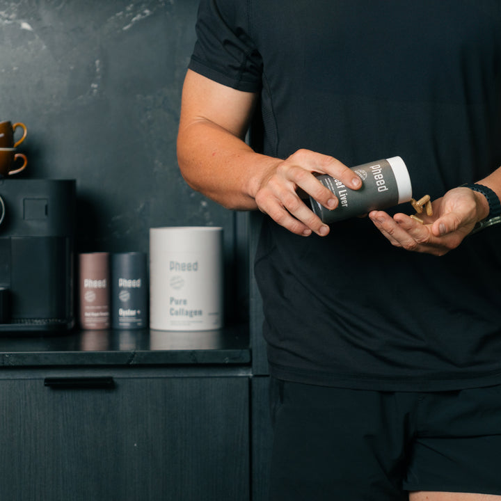 Man tipping out Beef Liver capsules into hand in a black kitchen with Beef Organ Complex, Oyster+ and Collagen in the background