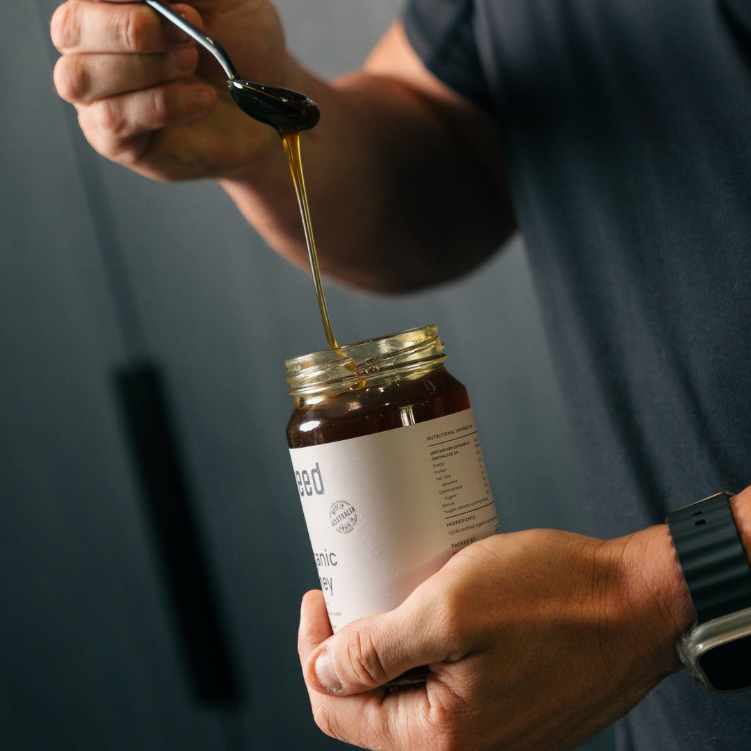 Man holding Pheed Organic Honey with a spoon dripping honey