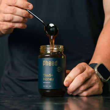 Close-up of TA45+ Organic Jarrah Honey in a glass jar, rich golden colour.